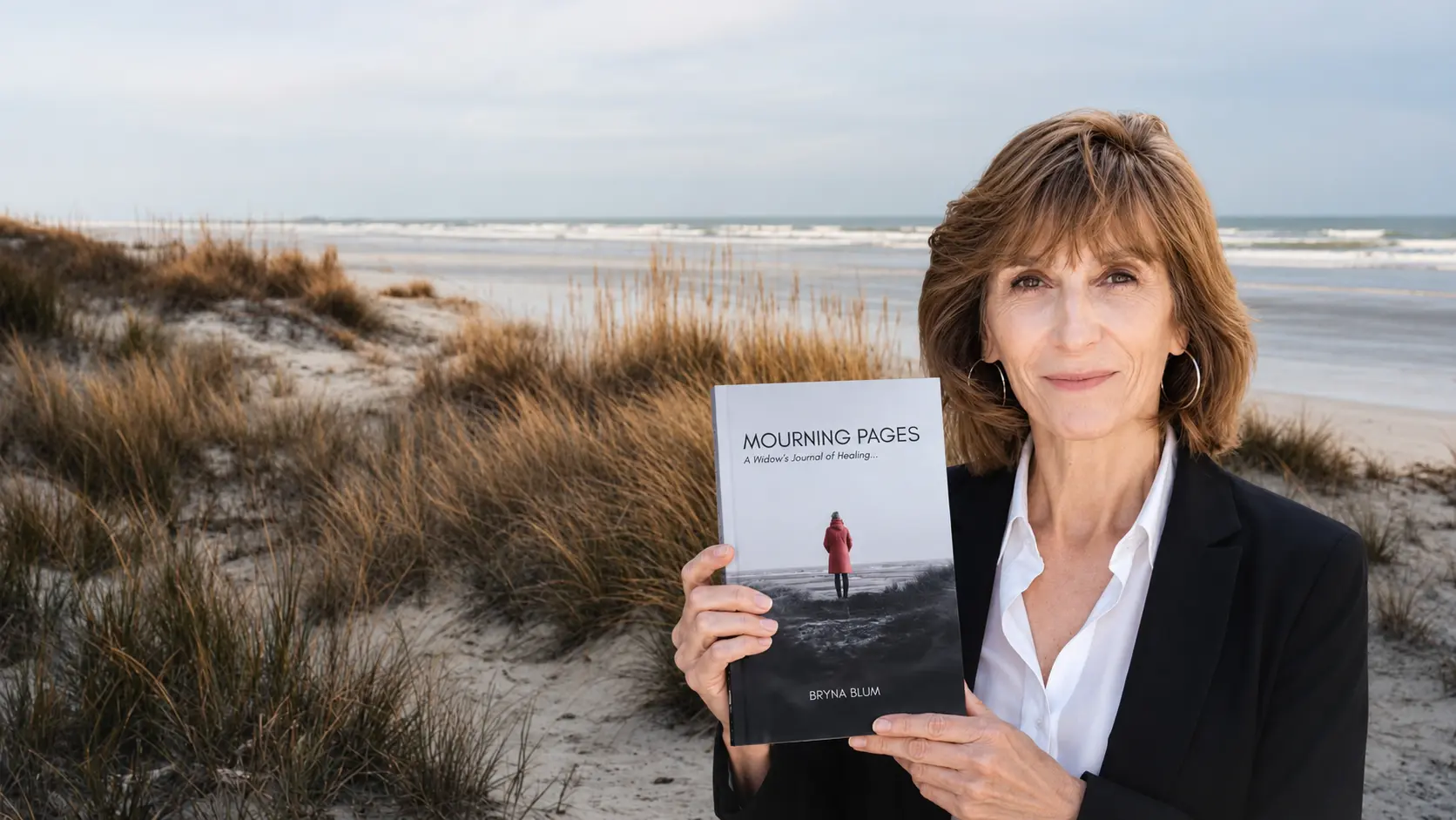 Bryna Blum hero homepage. Holding her book with a seascape in the background.